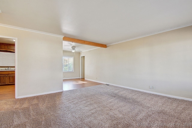 carpeted empty room featuring crown molding, sink, ceiling fan, and beam ceiling