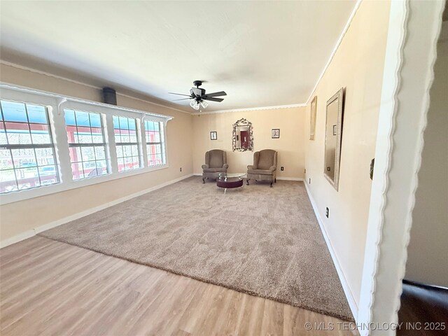 unfurnished room featuring electric panel, wood finished floors, baseboards, ceiling fan, and ornamental molding