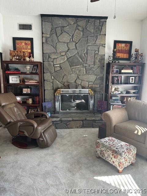 carpeted living room featuring ceiling fan and a fireplace