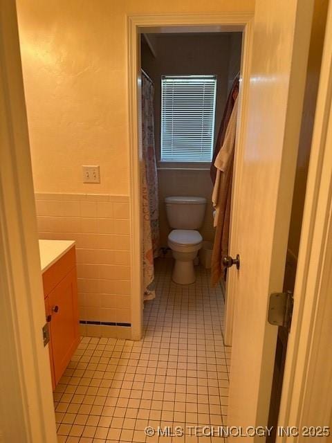 bathroom with tile patterned floors, toilet, vanity, and tile walls