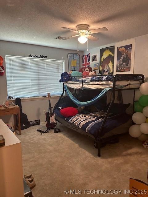 carpeted bedroom featuring ceiling fan and a textured ceiling