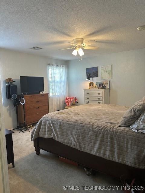 bedroom featuring ceiling fan, light colored carpet, and a textured ceiling