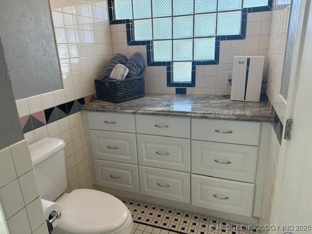 bathroom with vanity, toilet, and tile walls