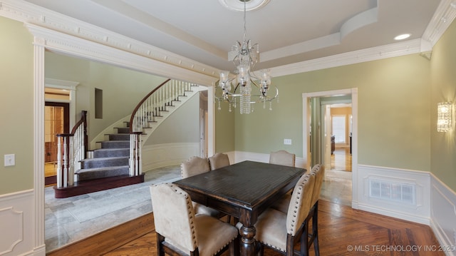 dining area featuring a chandelier, ornamental molding, a raised ceiling, and dark wood-type flooring