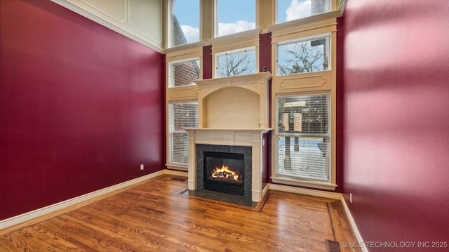 unfurnished living room featuring a towering ceiling, wood-type flooring, and a high end fireplace