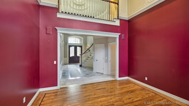 entrance foyer featuring hardwood / wood-style flooring, a towering ceiling, and french doors