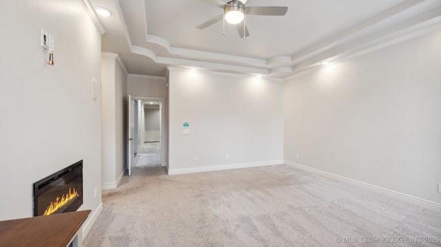 unfurnished living room featuring ornamental molding, light colored carpet, a raised ceiling, and ceiling fan