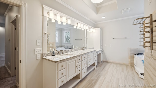 bathroom with vanity, a washtub, ornamental molding, and a raised ceiling