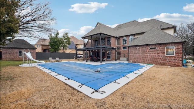 view of pool featuring a patio, a water slide, and a lawn