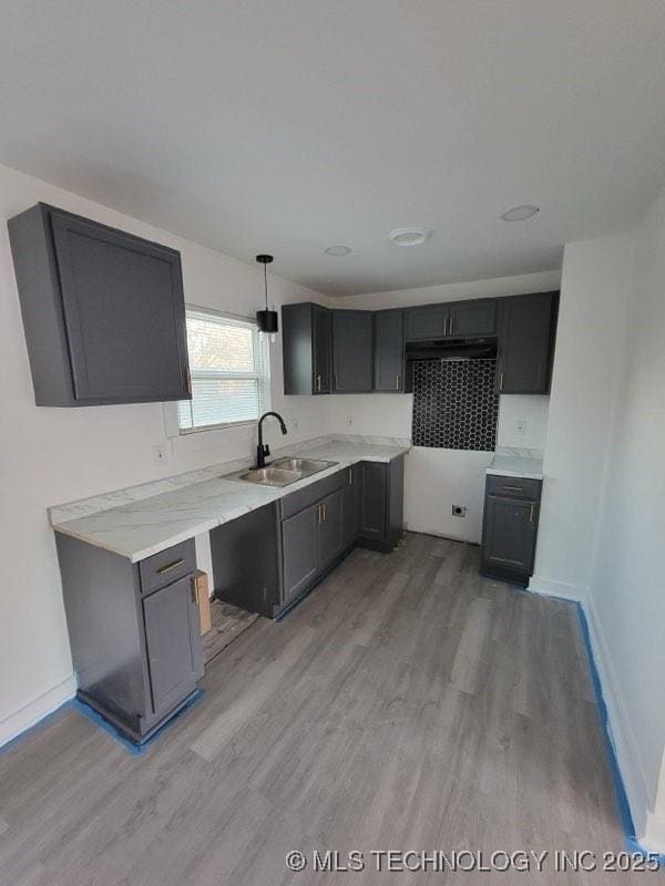 kitchen featuring sink, hanging light fixtures, and light wood-type flooring