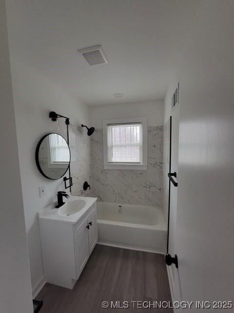 bathroom with vanity, hardwood / wood-style flooring, and tiled shower / bath combo