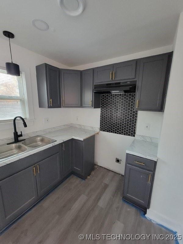 kitchen featuring light stone counters, sink, decorative light fixtures, and dark wood-type flooring