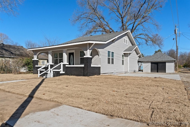 view of front facade with a garage, an outbuilding, covered porch, and a front lawn