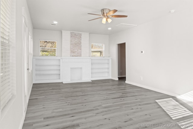 unfurnished living room featuring a brick fireplace, hardwood / wood-style flooring, and ceiling fan