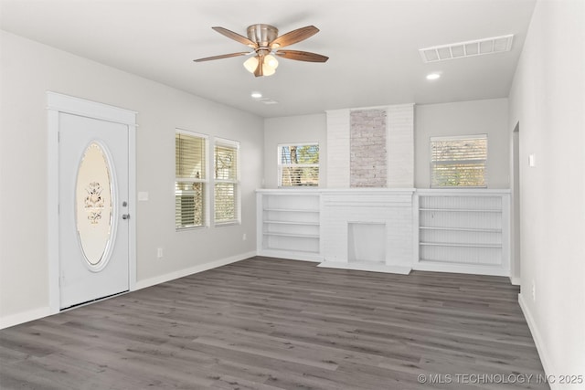 entryway featuring ceiling fan, a fireplace, dark hardwood / wood-style flooring, and a wealth of natural light