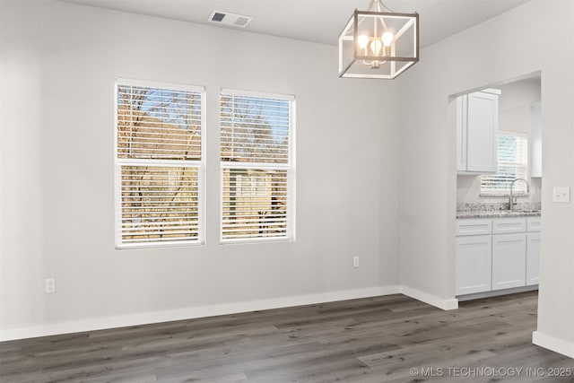 unfurnished dining area featuring sink, an inviting chandelier, and dark hardwood / wood-style flooring