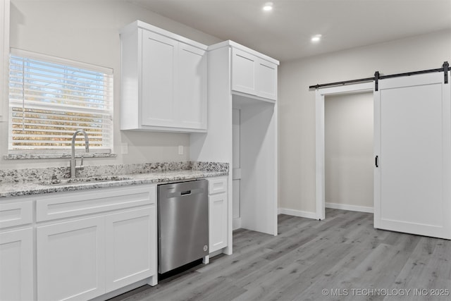 kitchen with white cabinetry, dishwasher, a barn door, and sink