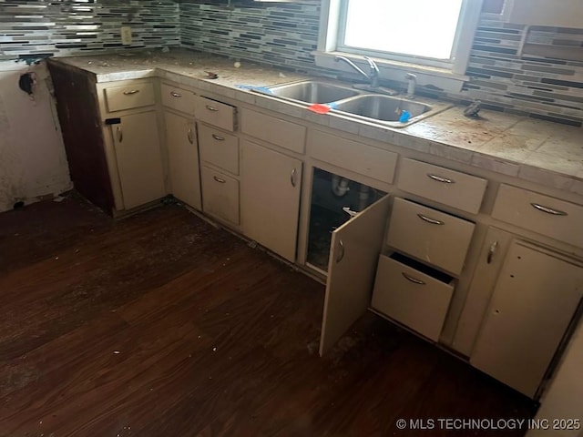 kitchen with tasteful backsplash, white cabinetry, sink, and dark wood-type flooring