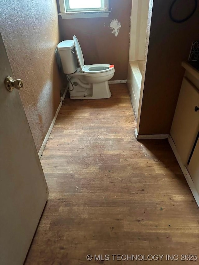 bathroom featuring hardwood / wood-style flooring, a washtub, and toilet