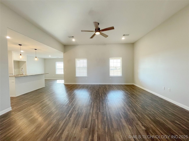 unfurnished living room with ceiling fan, dark hardwood / wood-style floors, sink, and a wealth of natural light