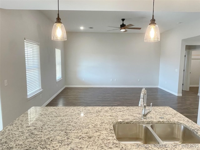 kitchen featuring light stone countertops, sink, dark hardwood / wood-style floors, and decorative light fixtures