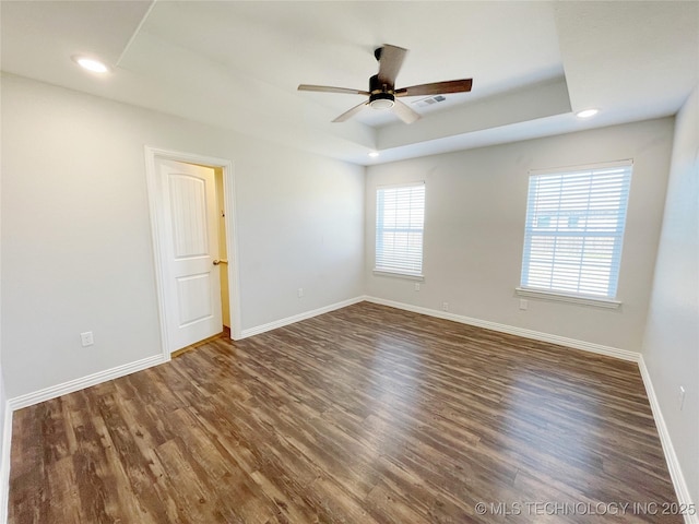 unfurnished room with ceiling fan, dark hardwood / wood-style floors, and a raised ceiling