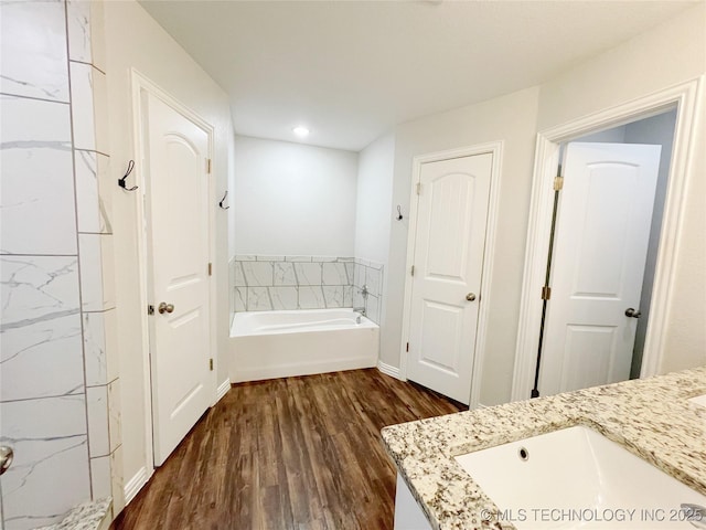 bathroom featuring hardwood / wood-style flooring, vanity, and a tub