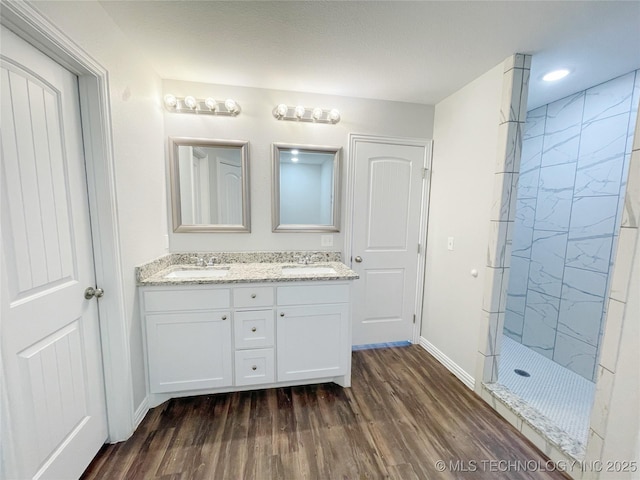 bathroom featuring wood-type flooring, a tile shower, and vanity