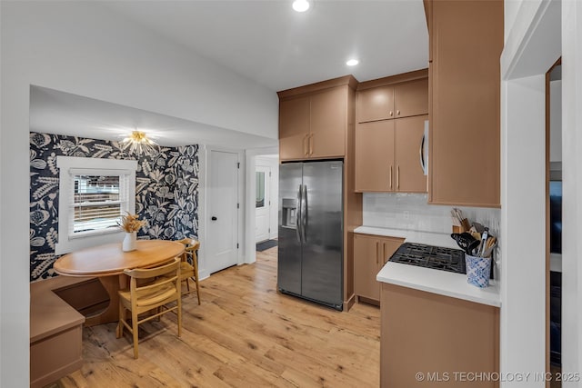 kitchen featuring backsplash, appliances with stainless steel finishes, light hardwood / wood-style flooring, and light brown cabinets