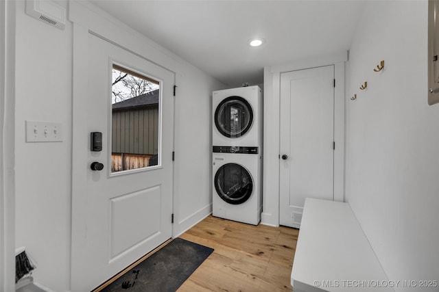 laundry room with stacked washer / drying machine and light hardwood / wood-style floors