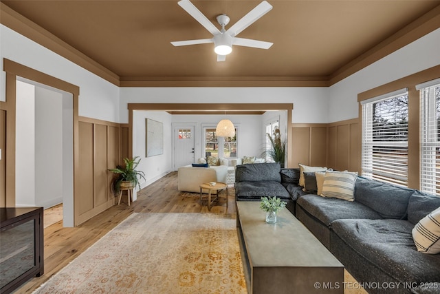 living room with crown molding, light hardwood / wood-style flooring, and ceiling fan