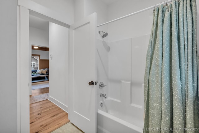 bathroom with hardwood / wood-style flooring and shower / bath combo with shower curtain