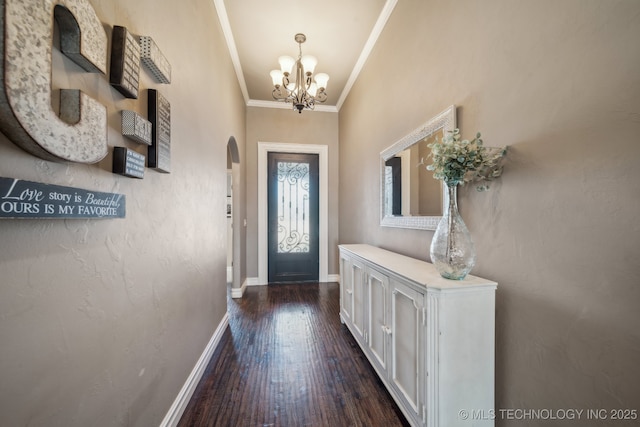 doorway to outside with dark wood-type flooring, ornamental molding, and a notable chandelier