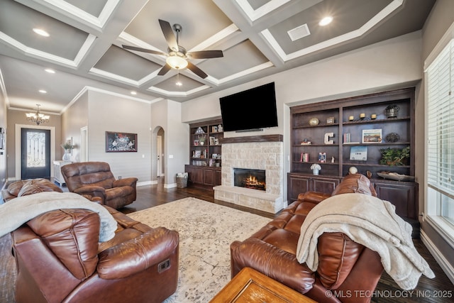 living room featuring crown molding, wood-type flooring, coffered ceiling, and a stone fireplace