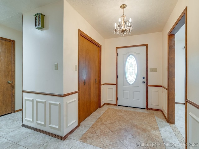 entryway with a chandelier, a textured ceiling, and light tile patterned floors