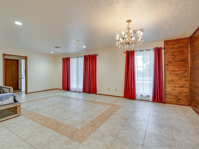 tiled empty room featuring an inviting chandelier and a textured ceiling