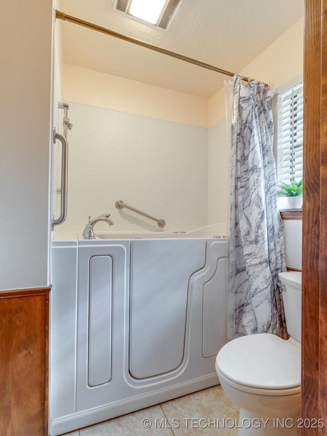 bathroom with tile patterned flooring, a bathtub, and toilet