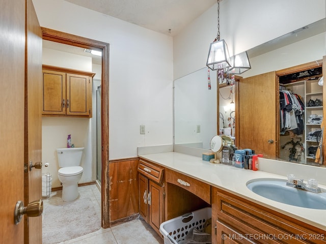 bathroom with tile patterned floors, vanity, toilet, and a shower with door