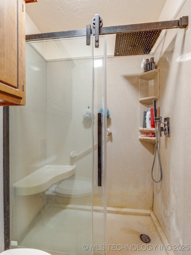 bathroom featuring a shower with door and toilet