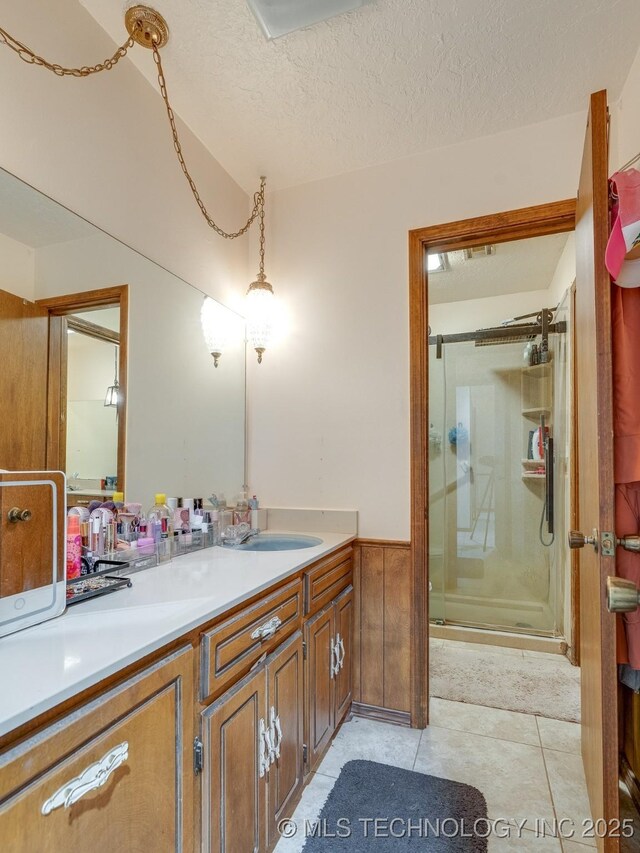 bathroom featuring tile patterned floors, vanity, a shower with door, and a textured ceiling