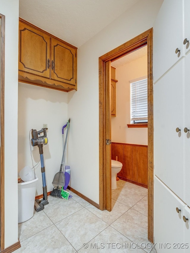 washroom with light tile patterned floors, wooden walls, and a textured ceiling