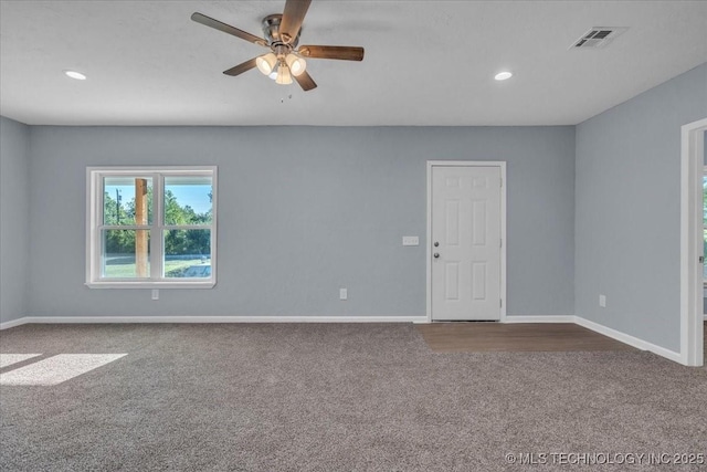 spare room with ceiling fan and dark colored carpet