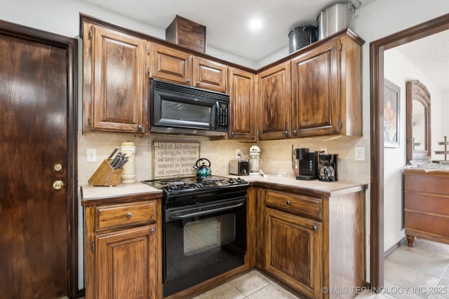 kitchen featuring tasteful backsplash, light tile patterned flooring, and black appliances