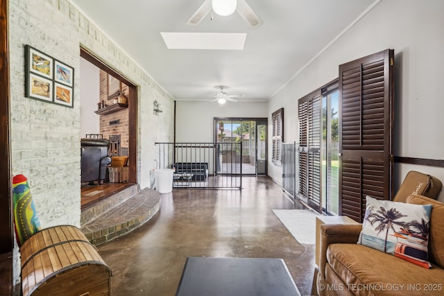 living room featuring concrete flooring, ornamental molding, ceiling fan, and a skylight