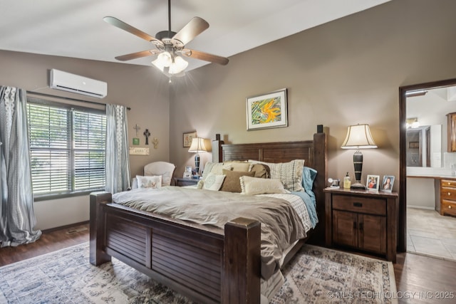 bedroom featuring ceiling fan, hardwood / wood-style flooring, a wall mounted AC, and ensuite bathroom