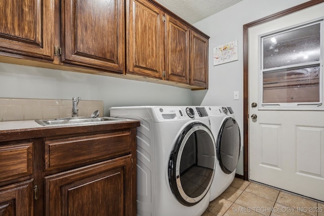 washroom with light tile patterned flooring, sink, cabinets, a textured ceiling, and washer and clothes dryer