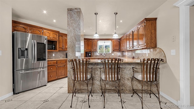 kitchen featuring stainless steel refrigerator with ice dispenser, a breakfast bar, kitchen peninsula, pendant lighting, and backsplash