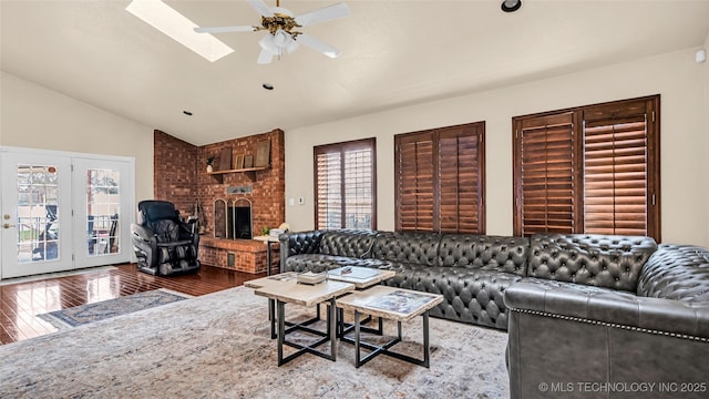 living room featuring a brick fireplace, lofted ceiling with skylight, hardwood / wood-style floors, and ceiling fan