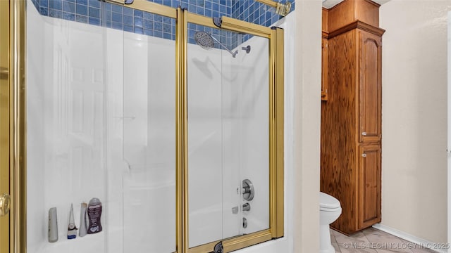 bathroom featuring tile patterned flooring, enclosed tub / shower combo, and toilet