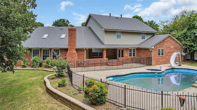 view of pool with a patio, a water slide, an in ground hot tub, and a lawn